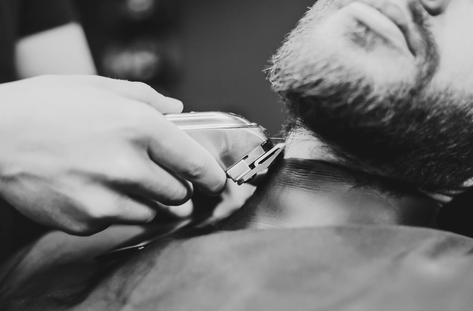 Barber trimming the neckline and beard with clippers